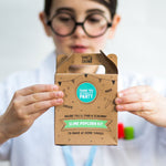 Child holding a "Slime Popcorn Kit" box, wearing glasses and a white shirt, focused on the packaging.